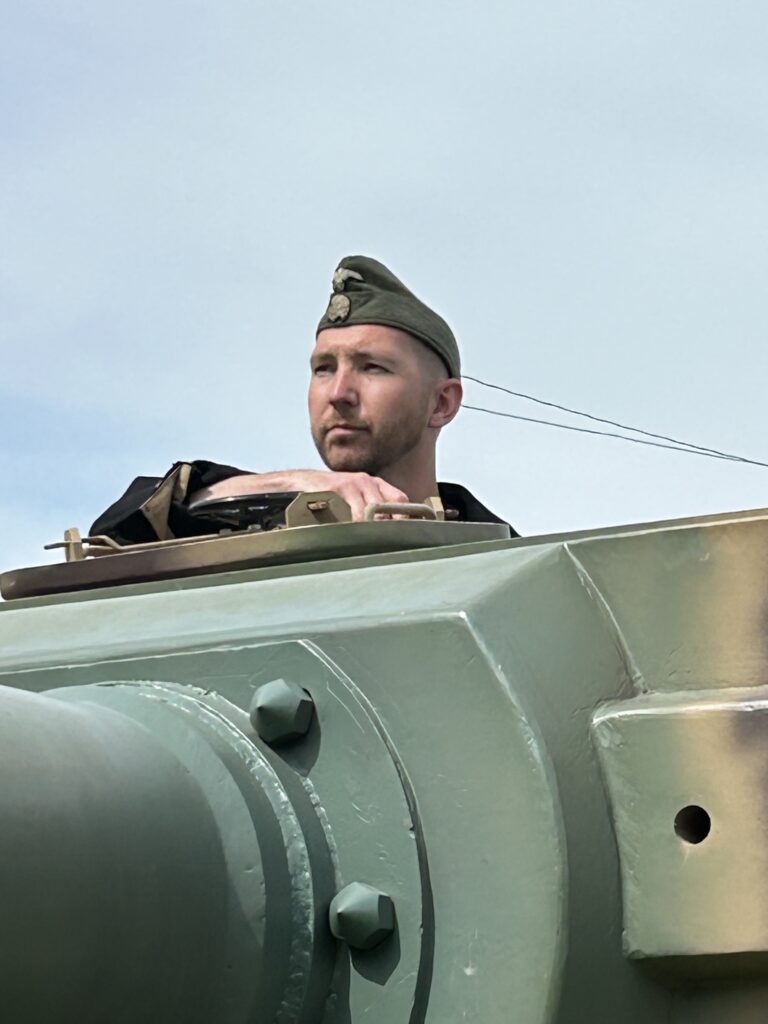 WWII historical reenactor looking out from a tank commander hatch during a live demonstration at Terra Bellum