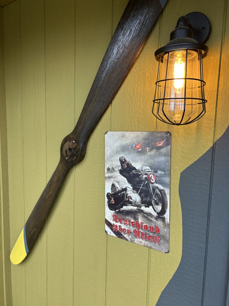 Vintage wooden airplane propeller and historical decor mounted on an exterior wall at Terra Bellum