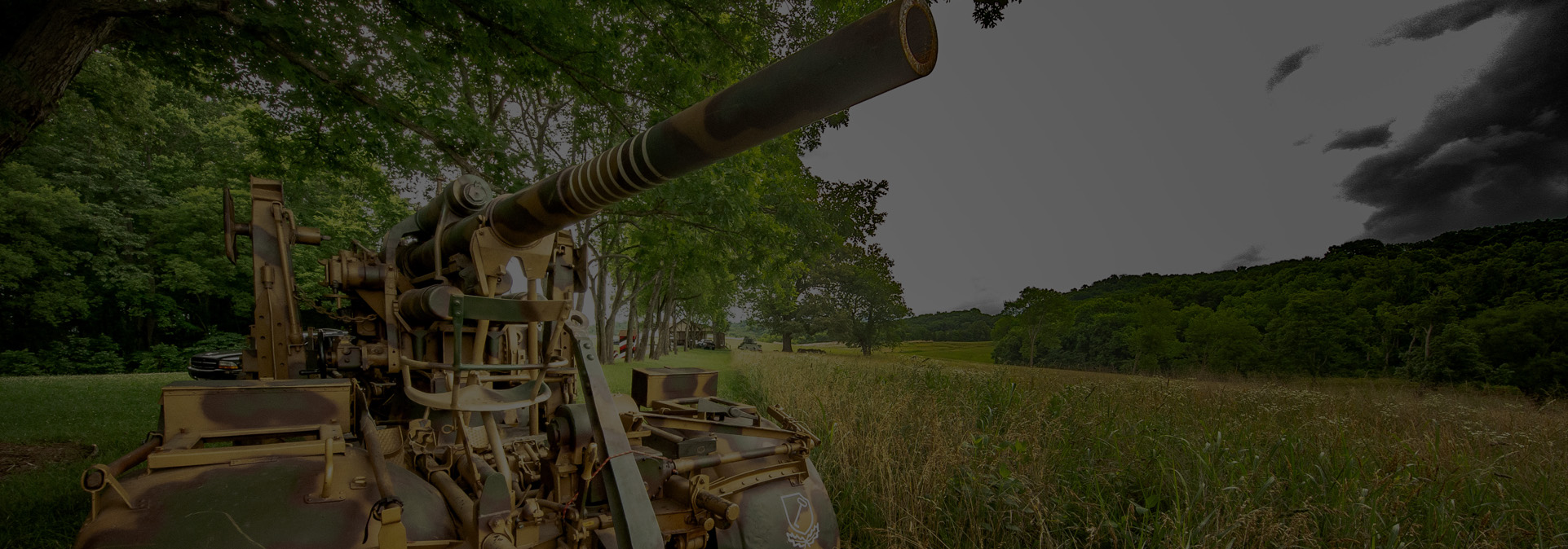 Vintage World War II military artillery piece overlooking the open grassy fields and event grounds at Terra Bellum