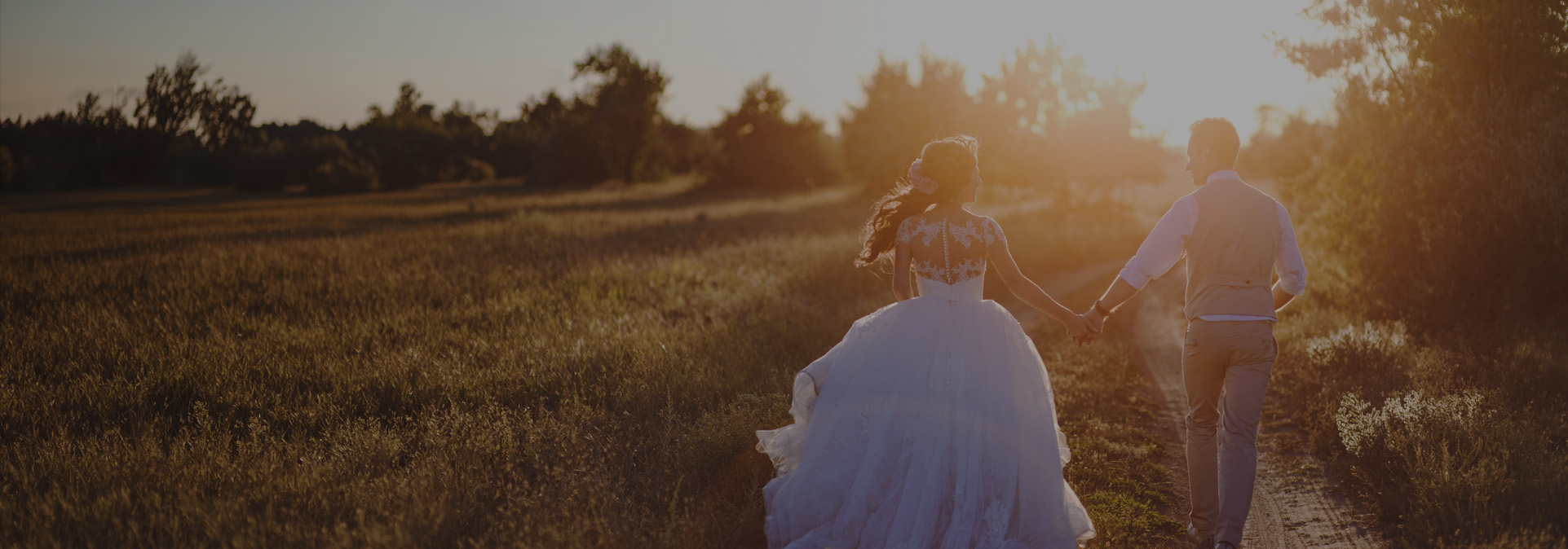 Bride and groom holding hands walking through an open field at sunset at Terra Bellum